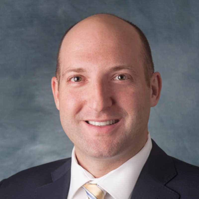a man wearing a suit and tie smiling at the camera