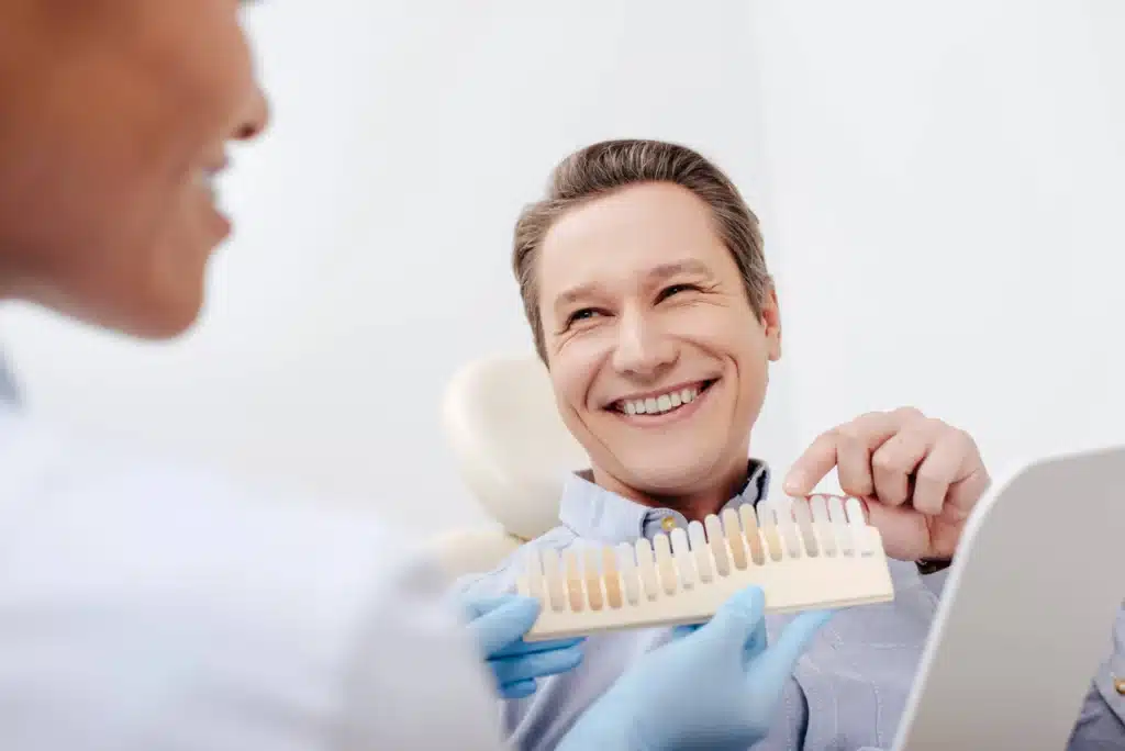 Man choosing his desired tooth shade with a brownstown cosmetic dentist